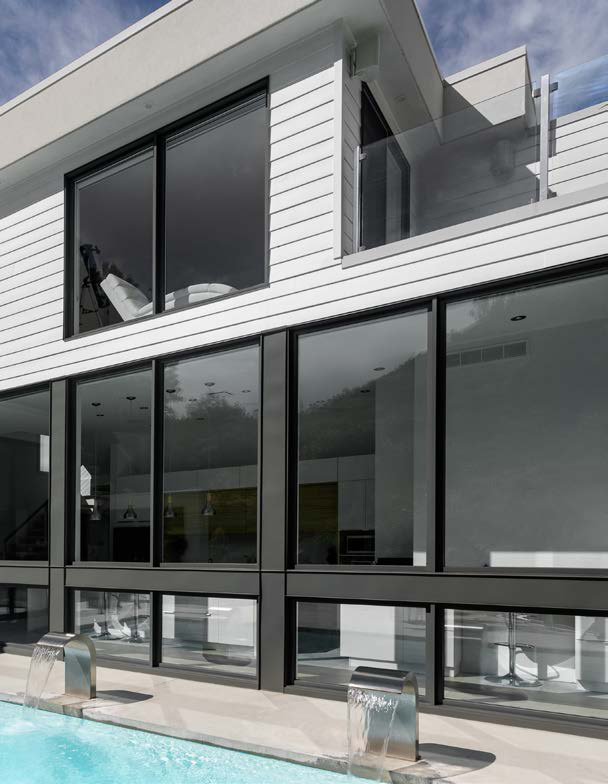 Maison contemporaine à grandes surfaces vitrées noires, au bord d'une piscine