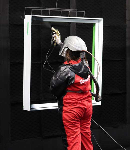 Une ouvrière applique la peinture sur un cadre de fenêtre à l'usine
