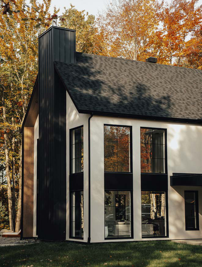 Grande fenêtre fixe noire sur une maison entourée d'arbres d'automne