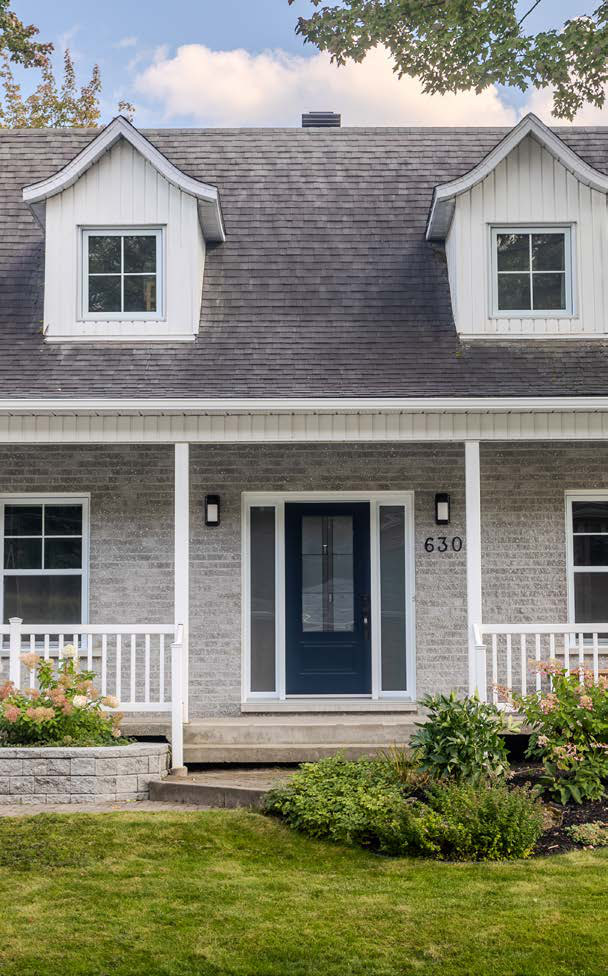 Maison canadienne grise à lucarnes, porte d'entrée bleu nuit