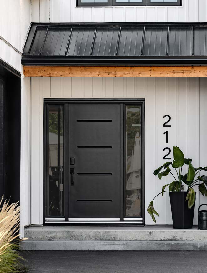 Porte d'entrée noire avec verres latéraux, numéro 212 sur un revêtement blanc