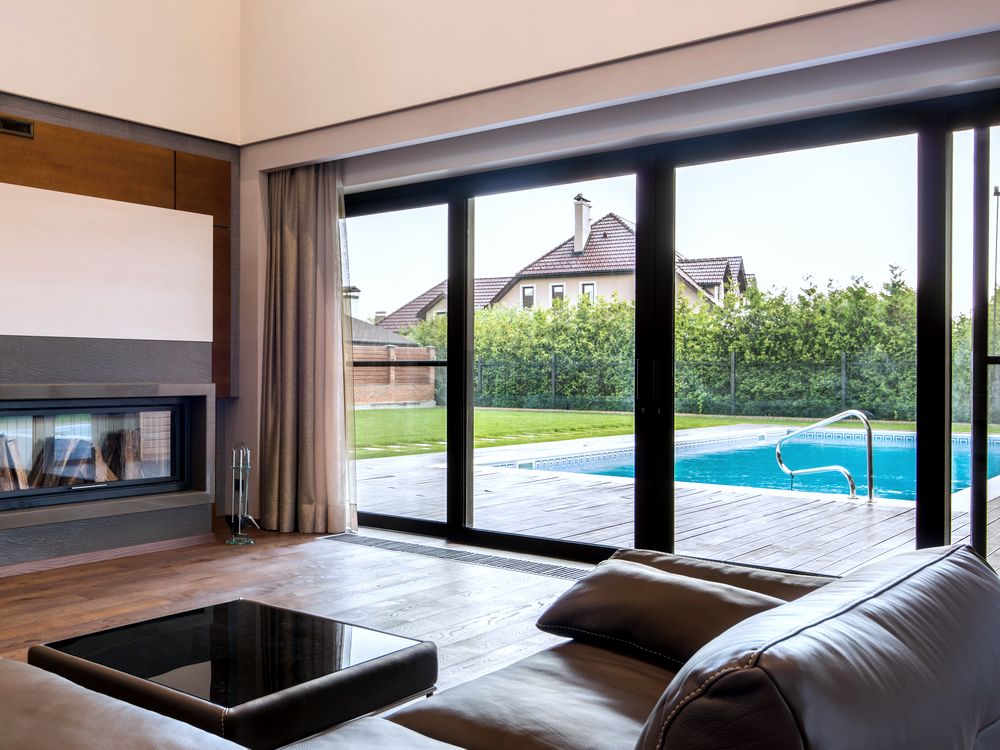 Porte patio coulissante noire ouverte sur une terrasse et une piscine